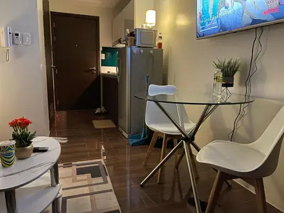 a kitchen with a glass table and chairs and a refrigerator at Destina Stays @Air Residences Makati, MetroManila in Manila
