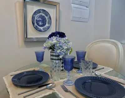 a table with blue plates and a vase of flowers at Uptown BGC Taguig - One Bedroom in Manila