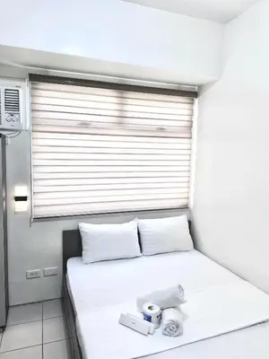 a small bedroom with a white bed with a window at Arkisha’s Cozy Place in Manila
