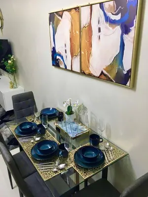 a dining table with blue plates and glasses and a painting at New & Modern Cozy 1BR w/ Balcony@BGC, WiFi 300MBPS in Manila
