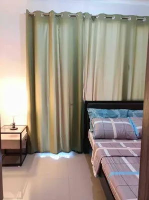 a bedroom with a bed with a curtain and a table at Shore 2 Staycation - Near Mall of Asia and Casinos in Manila