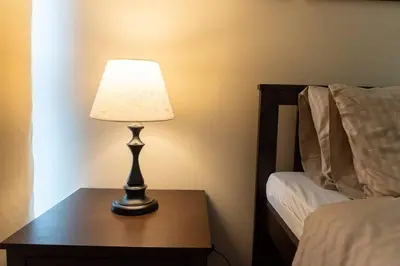 a lamp sitting on a table next to a bed at A2J Luxury Uptown 3BR Suite Near Uptown Mall in Manila