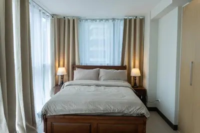 a bedroom with a bed with two lamps and windows at A2J Luxury Uptown 3BR Suite Near Uptown Mall in Manila