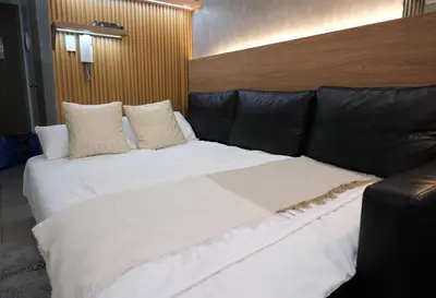 a large bed in a room with a leather couch at Staycation near Mall of Asia, Condotel with King Bed in Manila