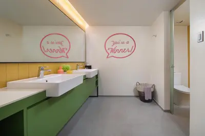 a bathroom with two sinks and two signs on the wall at lyf Malate Manila managed by The Ascott Limited in Manila