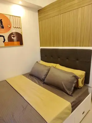 a bed with yellow and grey pillows in a bedroom at Skyia's Pod a Premier Suite at Shore 2 Residences in Manila