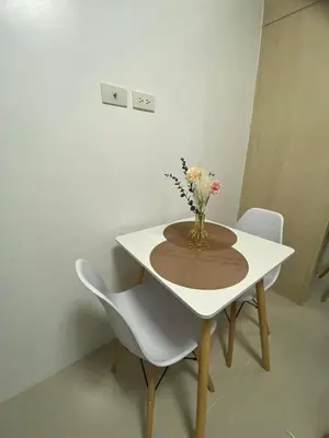 a white table with a vase of flowers on it at Casa Lim SMDC Light Residences Tower 3 in Manila
