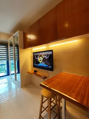 a kitchen with a table and a tv on the wall at Sea Residences 5mins walk to SM MoA, Arena, SMX, 55