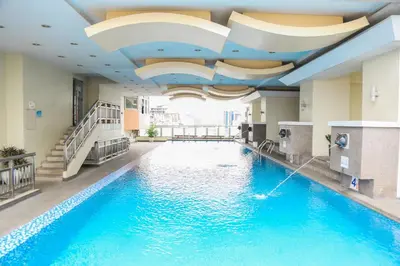 a swimming pool in a hotel with a ceiling at Pacific Bay Grand Suites in Manila