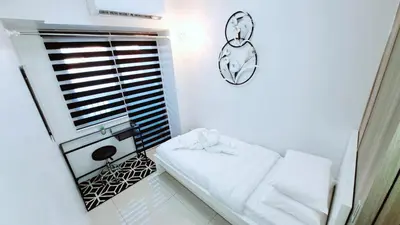 a small white room with a bed and a mirror at Stunning 1-Bedroom Condo in Manila