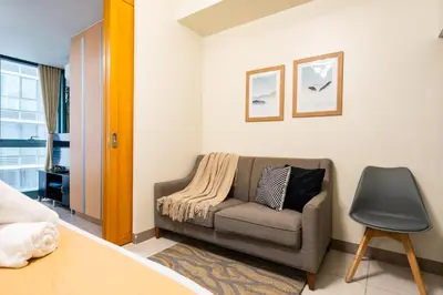 a living room with a couch and a chair at One Uptown Residence 1Br 2Bed Affordable for 4,Uptown Mall Linked in Manila