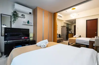 a hotel room with a bed and a flat screen tv at One Uptown Residence 1Br 2Bed Affordable for 4,Uptown Mall Linked in Manila