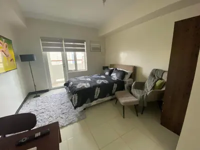 a bedroom with a bed and a chair at AMAZING VIEWS ACROSS SHANGRILA MALL and NEAR MEGAMALL GREENFIELD DISTRICT in Manila