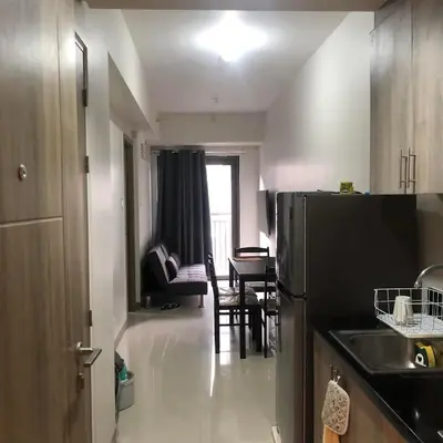 a kitchen with a black refrigerator and a living room at Cozy 1 Bedroom with balcony facing pool near MOA,IKEA near in Manila