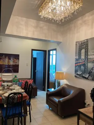 a living room with a table and a chandelier at Clazzy Home At San Lorenzo in Manila
