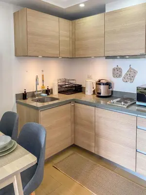 a kitchen with wooden cabinets and a sink and a table at nJoy! CHIC & Luxury at Venice Grand Canal in Manila