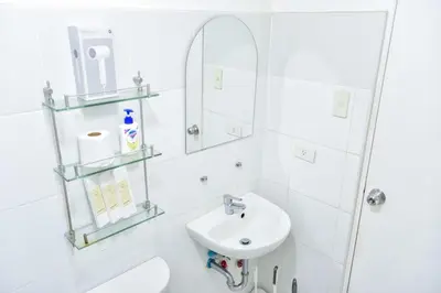 a white bathroom with a sink and a mirror at Lovely Modern 2BR Condo in Aurora Gardens San Juan City in Manila