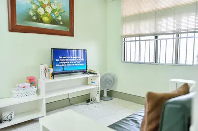a living room with a television on a white shelf at Lovely Modern 2BR Condo in Aurora Gardens San Juan City in Manila