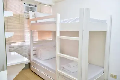a white bunk bed in a small room at Lovely Modern 2BR Condo in Aurora Gardens San Juan City in Manila
