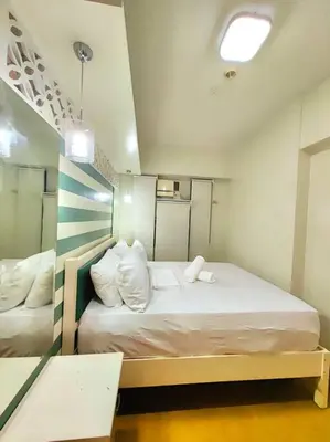 a small room with a bed with white pillows at Lovely Modern 2BR Condo in Aurora Gardens San Juan City in Manila
