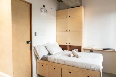 a bedroom with a bed and a wooden cabinet at HomeBase Apartment Hotel in Manila