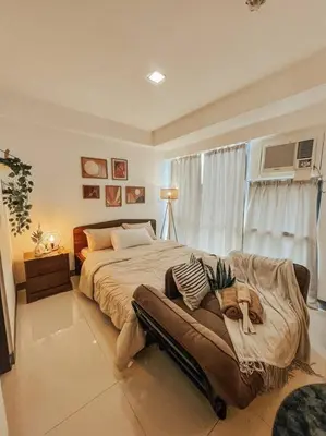 a bedroom with a bed with a dog sitting on a couch at Chic and Cozy Studio Viceroy Residences Taguig in Manila
