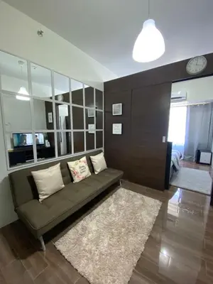 a living room with a couch and a clock on the wall at Air Residences 1-Bedroom condo in Makati in Manila