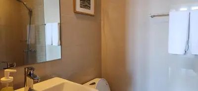 a bathroom with a toilet and a sink and a shower at Casa Antonio At Uptown Parksuites Two in Manila