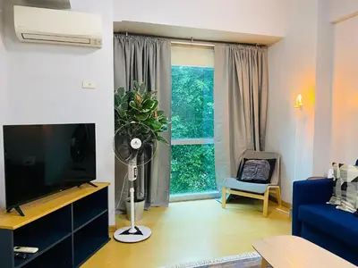 a living room with a tv and a blue couch at Avant at the Fort by Urban Realty in Manila