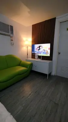 a living room with a green couch and a flat screen tv at ADB Avenue Tower Ortigas Manila in Manila