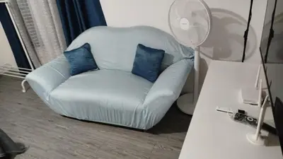 a white chair with blue pillows in a living room at ADB Avenue Tower Ortigas Manila in Manila