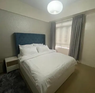 a bedroom with a bed with a blue headboard and a window at 150 Newport Blvd - Near T3 Airport in Manila