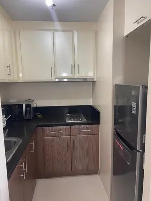 a kitchen with wooden cabinets and a black refrigerator at 150 Newport Blvd - Near T3 Airport in Manila