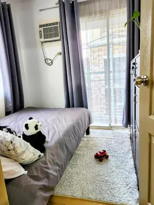 a bedroom with a bed with a panda bear pillow and a window at Amari Homestay @ Sorrento Oasis Condominium in Manila