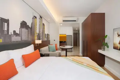 a bedroom with a large white bed with orange accents at Citadines Benavidez Makati in Manila