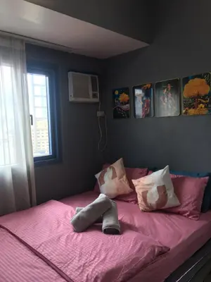 a bed with pink sheets and pillows and a window at Simple & Cozy 1 Bedroom US Embassy, Roxas Blvd, Ermita, Manila in Manila