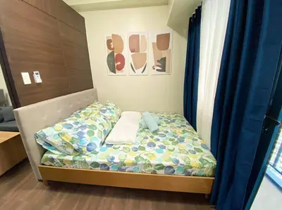 a small bed in a room with blue curtains at Air Residences with Fast Wifi in Manila
