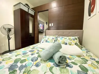 a bedroom with a bed with a floral bedspread and a fan at Air Residences with Fast Wifi in Manila