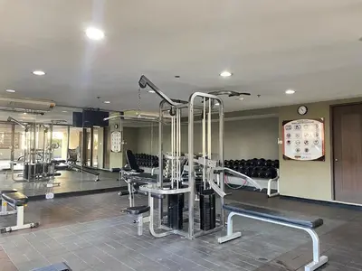 a gym with several treadmills and chairs and a clock at Mosaic 10H - Greenbelt Studio in Manila