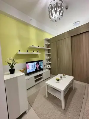 a living room with a tv and a white table at Night Blink Staycation and Rentals in Manila
