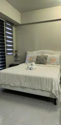 a bedroom with a white bed with towels on it at One Palm and Two Palm Tree Villas in Manila