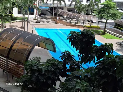 a blue swimming pool with chairs in a building at Bright and Cozy 1 Bedroom with Balcony Pool View and WiFi in Grace Residences in Manila