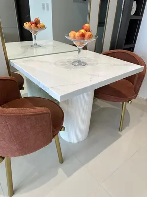 a white table with two chairs and a bowl of fruit at Uptown Parksuites BGC in Manila