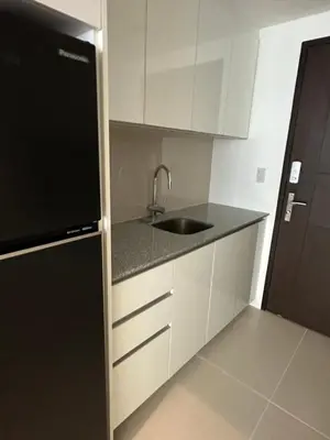 a kitchen with a sink and a black refrigerator at Uptown Parksuites BGC in Manila