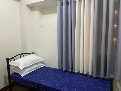 a bedroom with a blue bed with a window with curtains at Prisma Residences - Celeste Bldg in Manila
