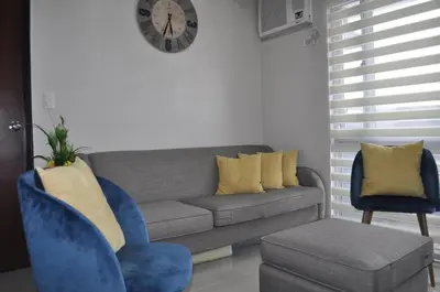 a living room with a couch and a clock on the wall at Casa De Camelina in Manila