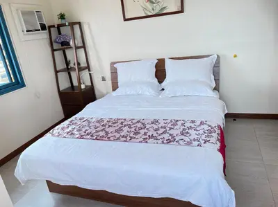 a bedroom with a white bed with a pink blanket on it at Grand Riviera Suites in Manila