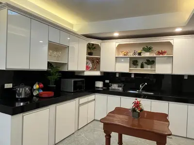 a kitchen with white cabinets and a wooden table at My Suite Heart of San Juan City near Greenhills, Ortigas with Roof Garden in Manila