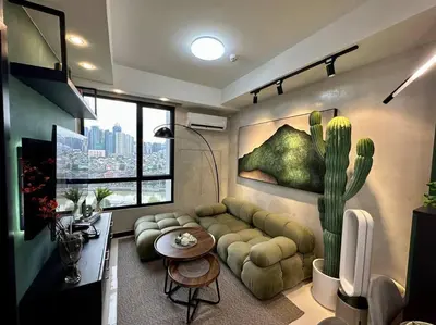 a living room with a couch and a cactus painting at The DRYM Space — Curated Staycation in Mandaluyong in Manila