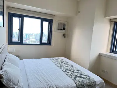 a bedroom with a bed and a window at Partial Ocean View Opposite the US Embassy in Manila